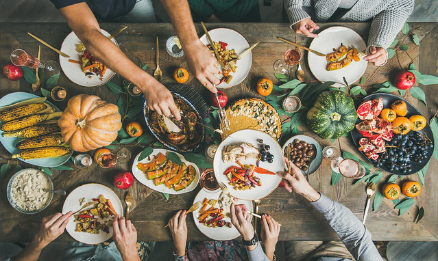 Traditional+Thanksgiving+or+Friendsgiving+holiday+celebration+party.+Flat-lay+of+friends+or+family+feasting+at+Thanksgiving+Day+festive+table+with+turkey%2C+pumpkin+pie%2C+roasted+seasonal+vegetables+and+fruit%2C+top+view.